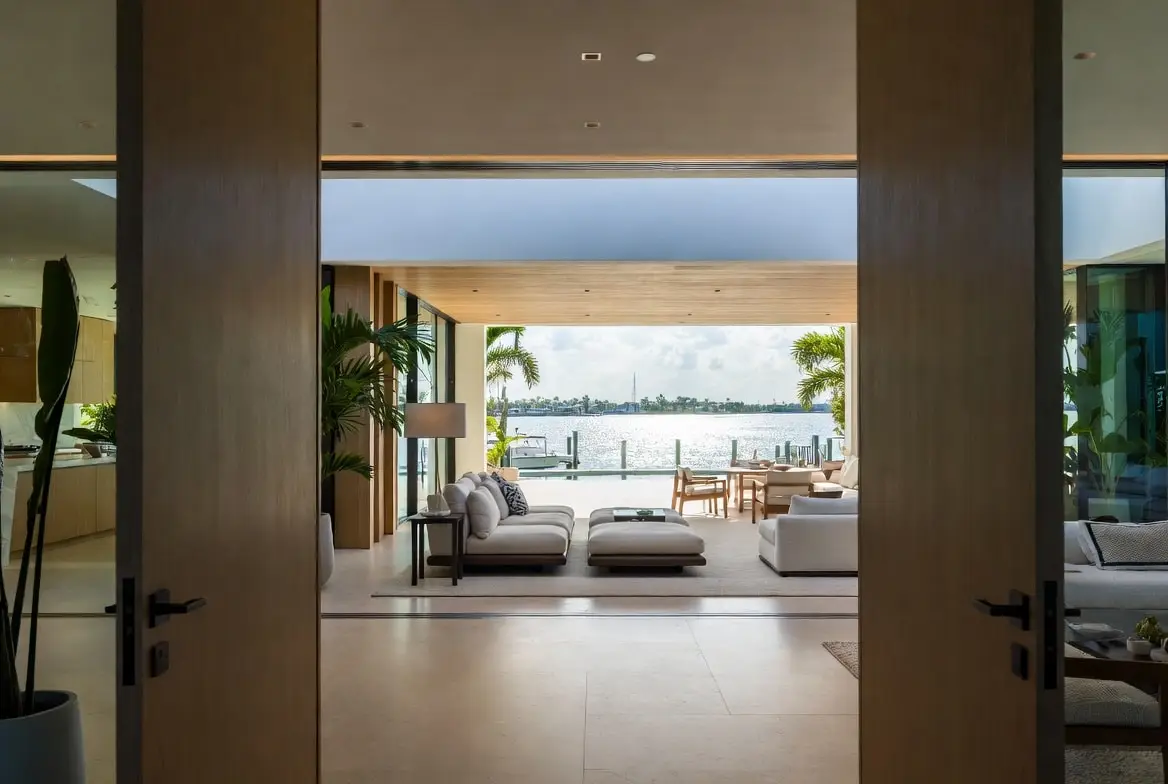 View corridor from the great room of a South Florida waterfront home straight through glass walls to the pool and canal
