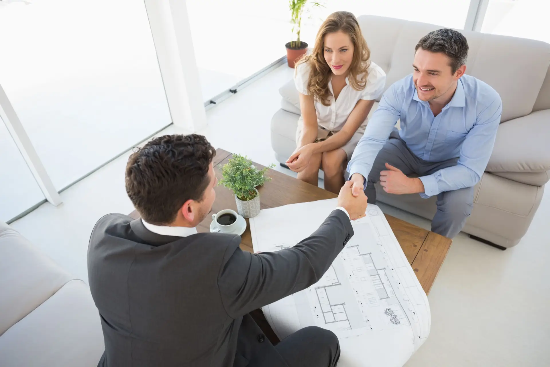 Owner's representative reviewing drawings with homeowners across a table during a project meeting