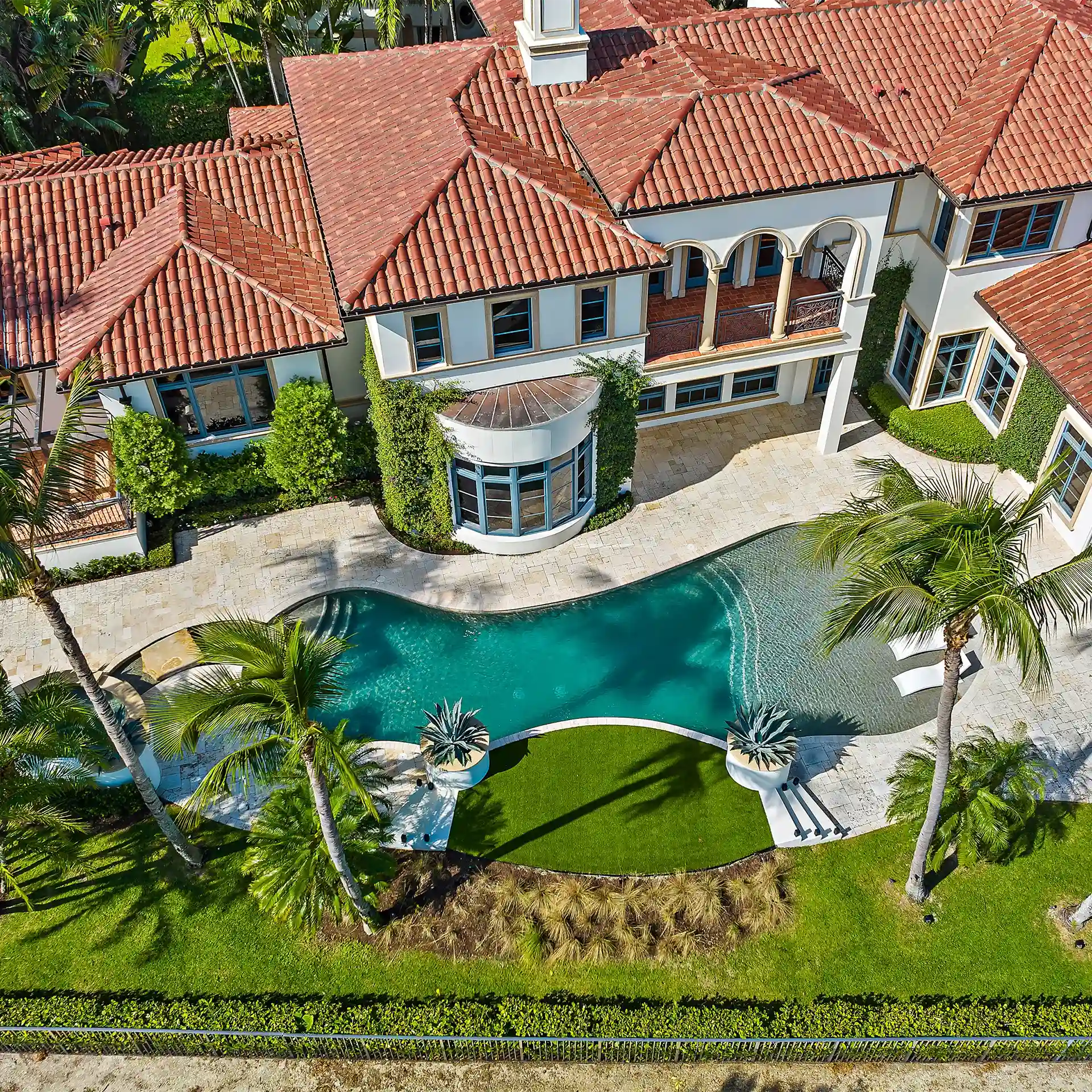 Aerial view of a South Florida luxury estate with tile roof, free-form pool, and mature landscaping